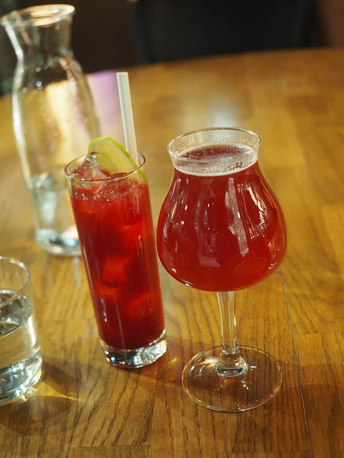 Twee alcoholvrije cocktails met rode kleur en limoen op een houten tafel